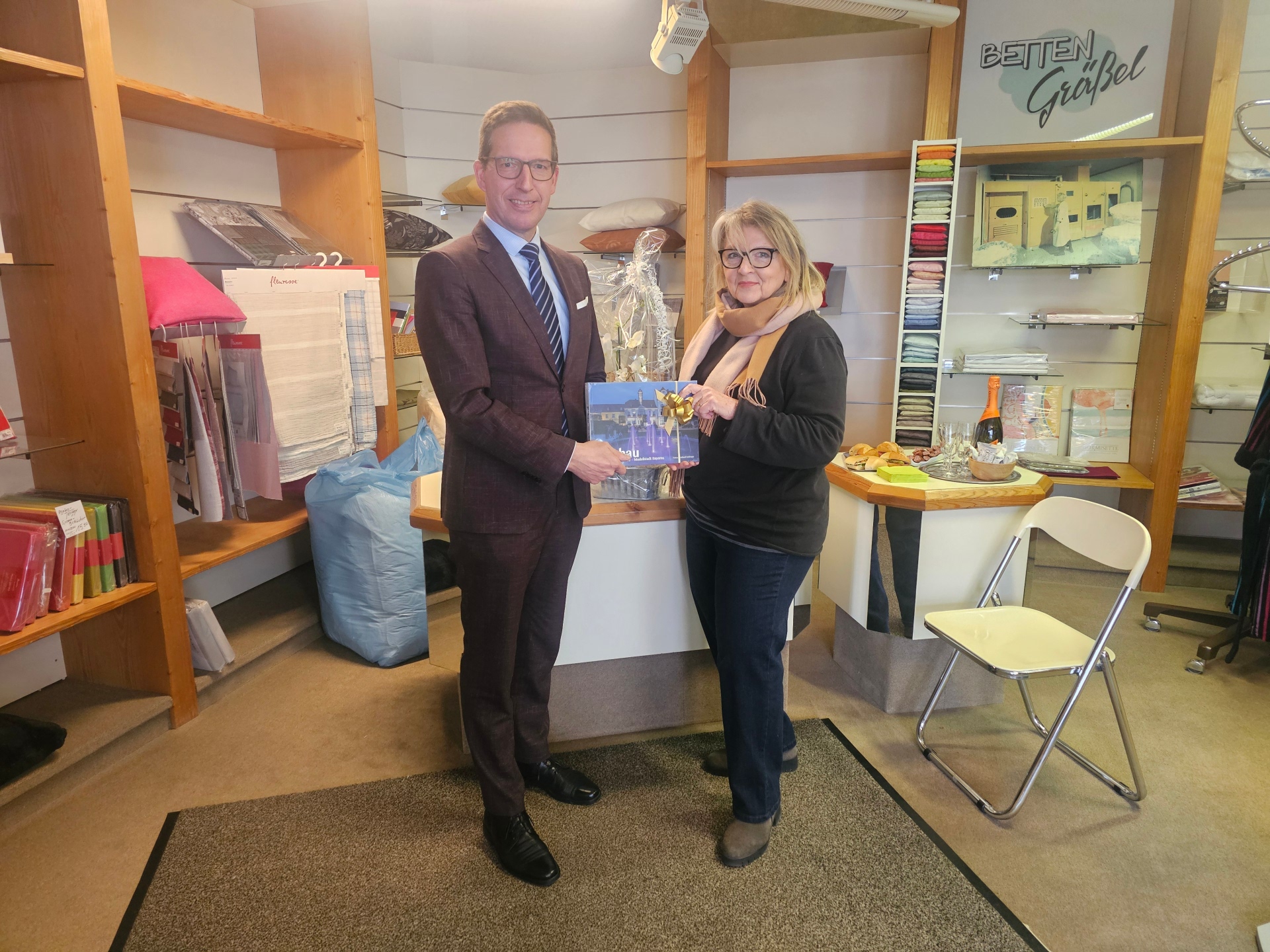 50 Jahre Betten Gräßel Der 1. Bürgermeister Michael Abraham beglückwünscht die Geschäftsinhaberin von Betten Gräßel, Marlene Kohrhammer, zum 50-jährigen Jubiläum und überreicht ein Geschenk.
