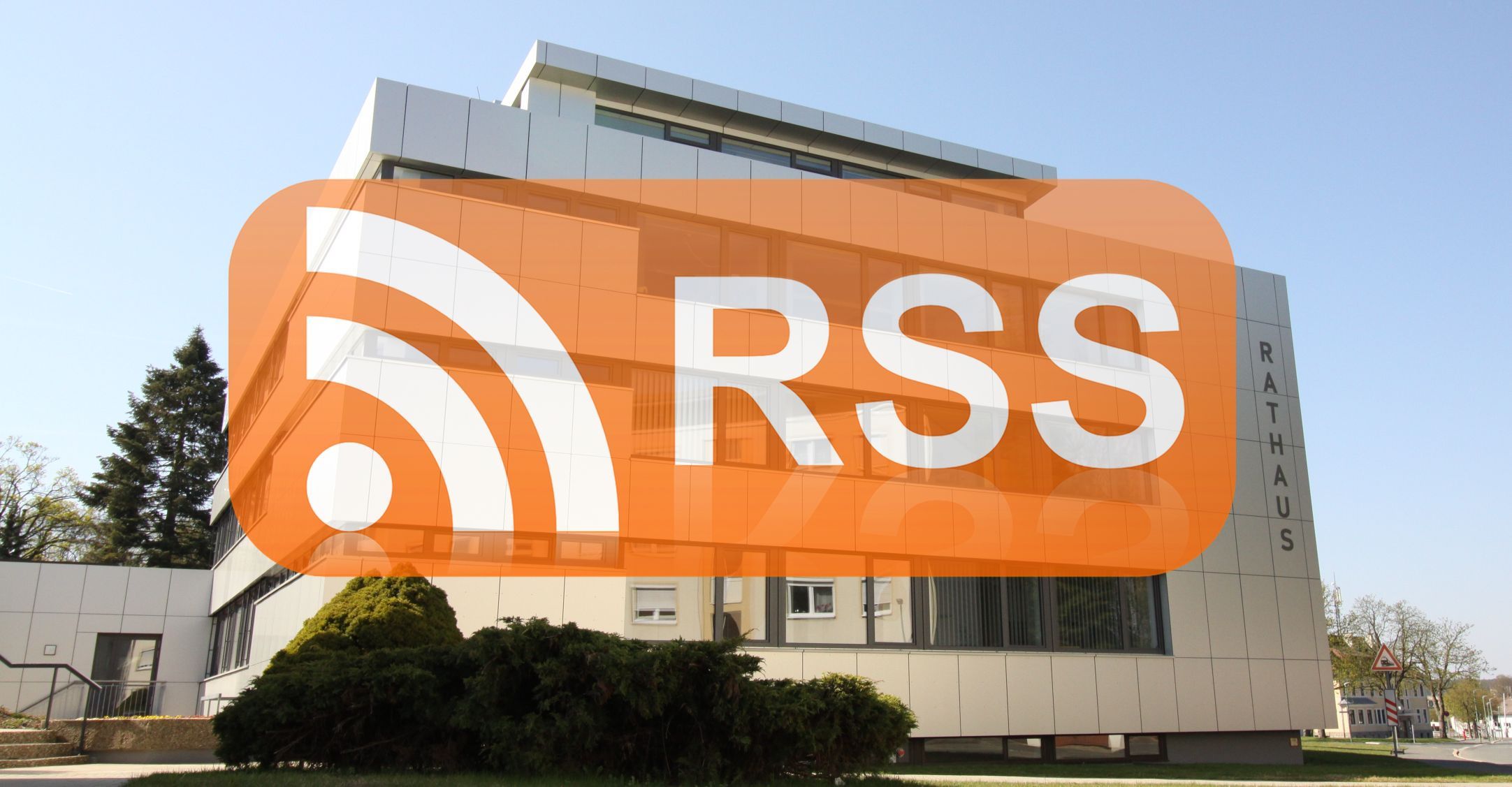 Das Bild zeigt im Hintergrund das Rathaus von der Unlitzstraße aus. Eine Ebene davor wurde das orangene Logo "RSS" eingefügt, das für den "RSS-Feed" steht.