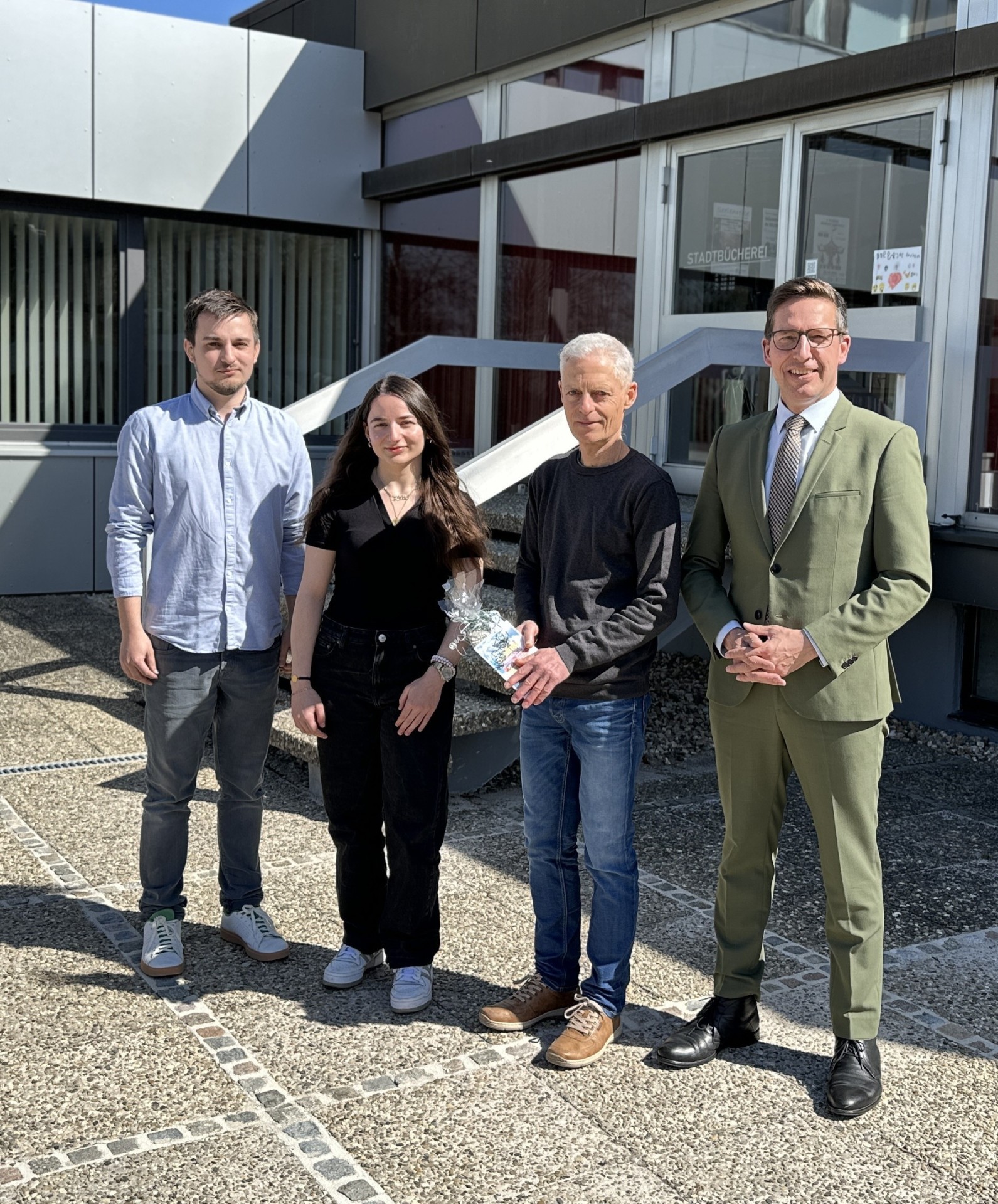Das Bild zeigt Oliver Groll, der von Bürgermeister Michael Abraham in den Ruhestand verabschiedet wird. Außerdem sind Michel Seifert und Melek Atmaca, das neue Team der Bücherei, zu sehen.