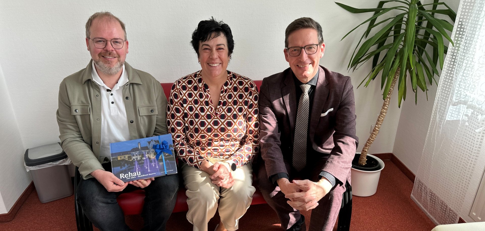 Auf dem Bild sind von links auf einem Sofa sitzend zu sehen: Zahnarzt Fabian Döhler, Zahnärztin Dr. Heike Ronneburg und Bürgermeister Michael Abraham