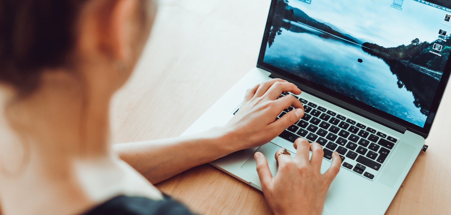Auf dem Bild ist eine Frau zu sehen, die gerade ihren Laptop bedient, der vor ihr steht.
