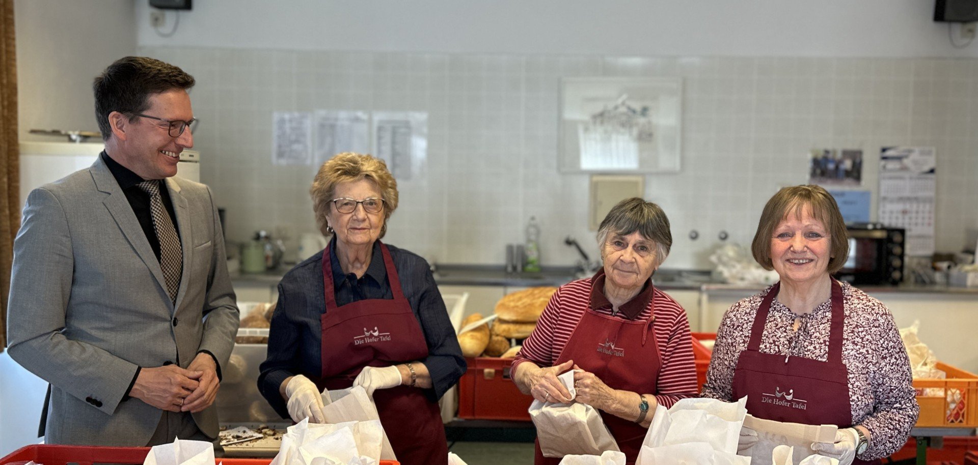 Das Bild zeigt Bürgermeister Michael Abraham neben Waltraud Rödel, Erika Kopp und Waltraud Marx, welche die Essensausgabe für die Hofer Tafel in Rehau vorbereiten.