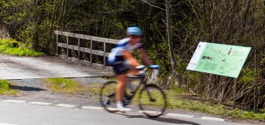 Das Bild zeigt einen Fahrradfahrer neben einer Infotafel der Perlenroute.