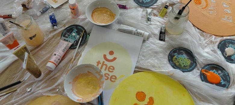 Das Bild zeigt gemalte Bilder mit dem Logo "The Base"