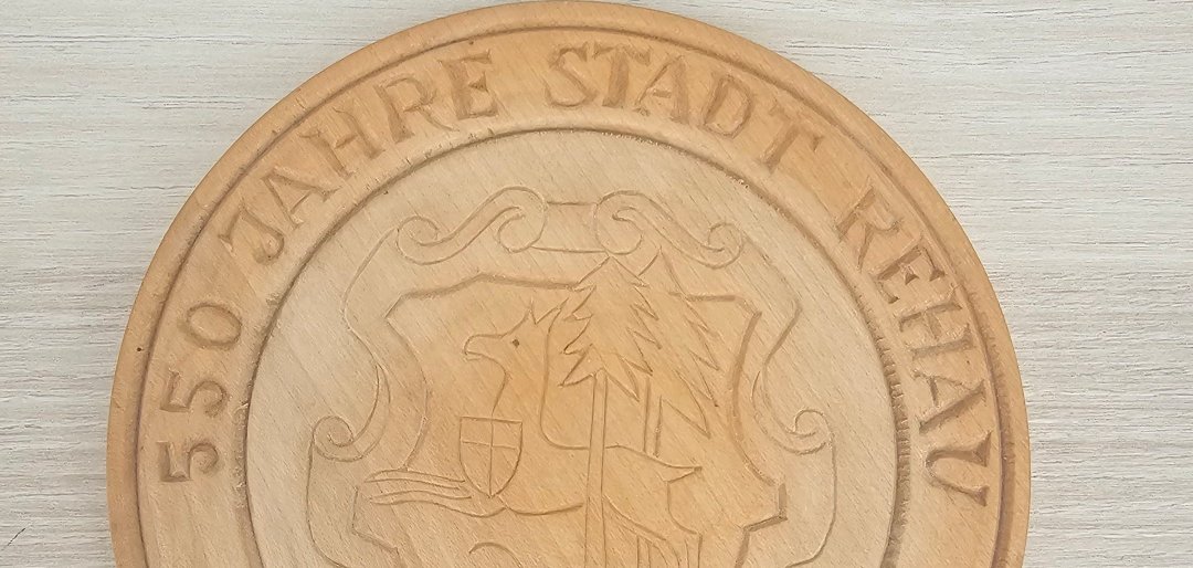 Auf dem Bild ist ein Holzstück mit dem Schriftzug "550 Jahre Stadt Rehau" zu sehen.