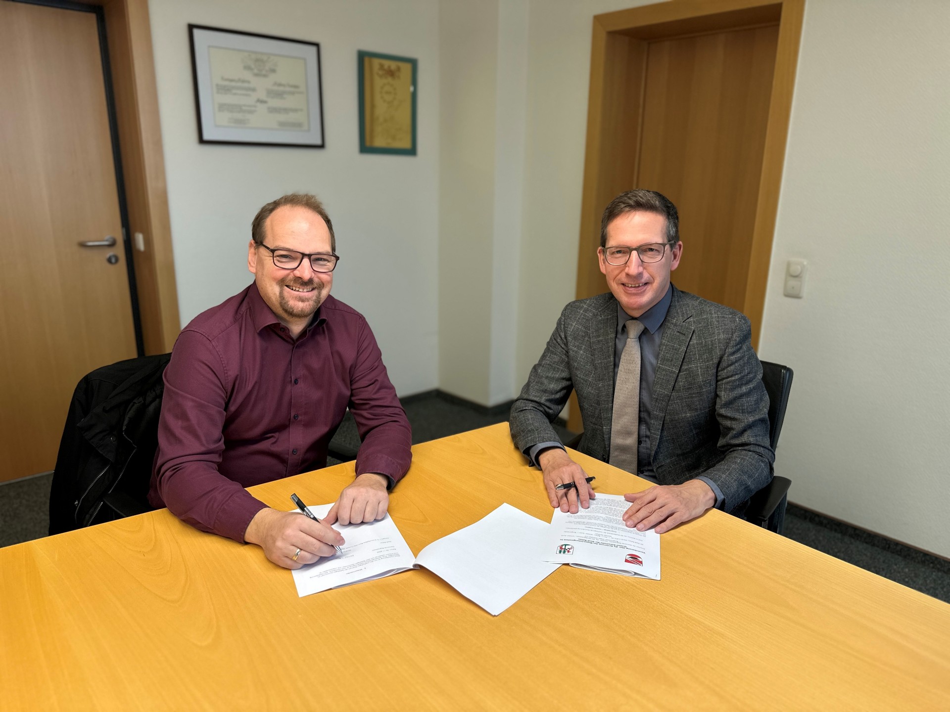 Das Bild zeigt Jürgen Schnabel und Michael Abraham bei der Unterzeichnung