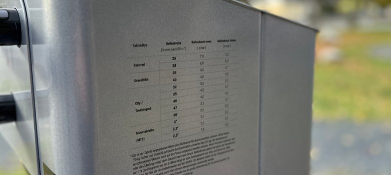Die Nahaufnahme zeigt die aufgedruckte Skala, welcher Fahrradtyp mit welcher Reifenbreite welchen Reifendruck vorn und hinten benötigt.