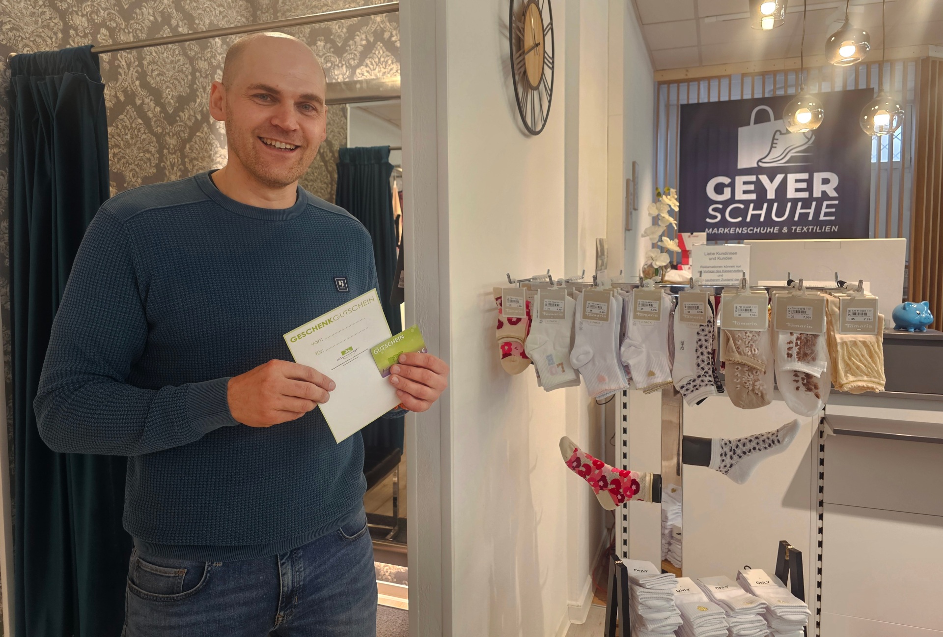 Gutscheine bei Geyer Schuhe Volker Dehling, Geschäftsführer von Geyer Schuhe hält den Gutschein der Werbegemeinschaft in der Hand.