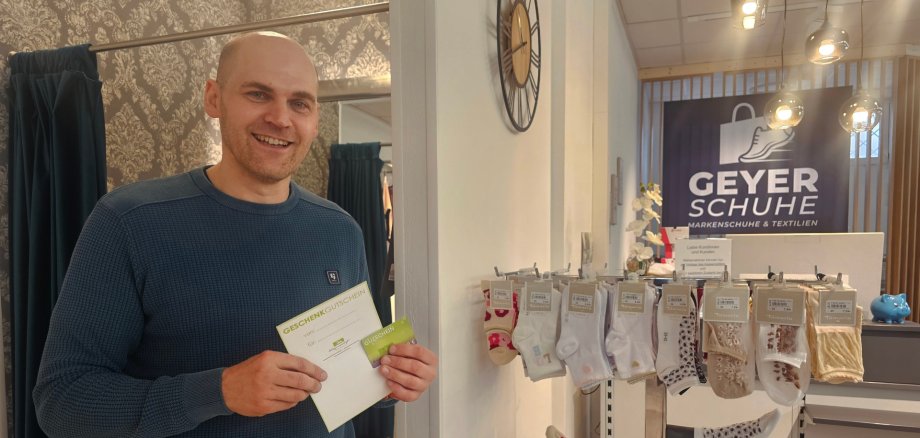 Volker Dehling, Geschäftsführer von Geyer Schuhe hält den Gutschein der Werbegemeinschaft in der Hand.