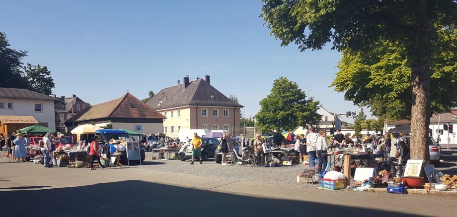 Blick vom Schützenhaus in Richtung Jahnstraße auf dem mit Flohmarkt-Ständen besetzten Parkplatz und Besucher.
