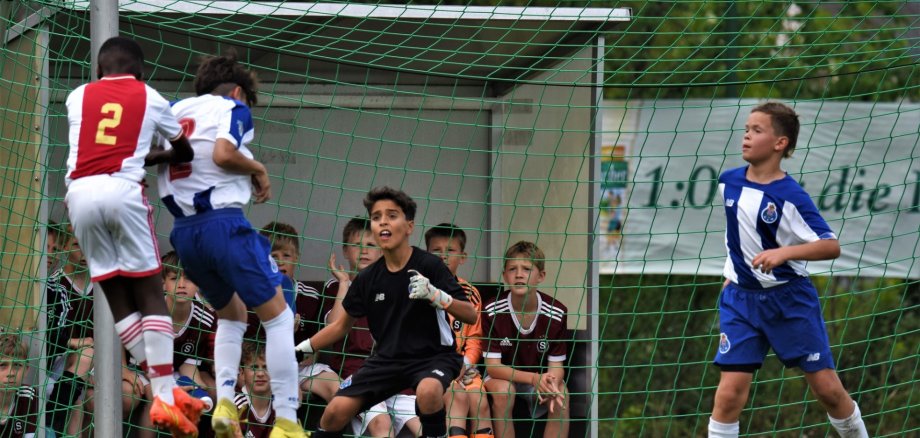 Auf dem Bild sind Jungs zu sehen, wie sie Fußball spielen. Augenscheinlich ist ein Spieler kurz davor auf das Tor zu schießen.