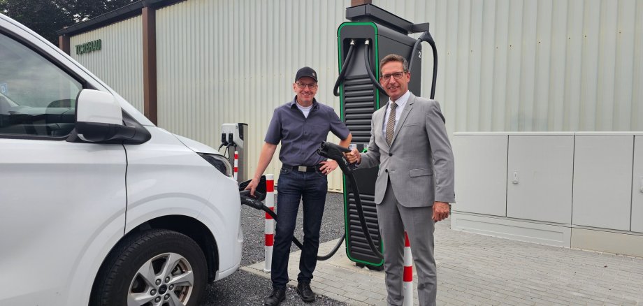 Auf dem Bild sind Bürgermeister Michael Abraham und Christian Dötsch bei der Einweihung der neuen E-Ladesäulen am Schützenfestplatz zu sehen.
