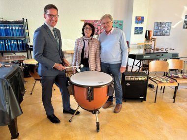 Bild zeigt Bürgermeister Michael Abraham neben Helma und Norbert Hofmann neben der neuen Kesselpauke.