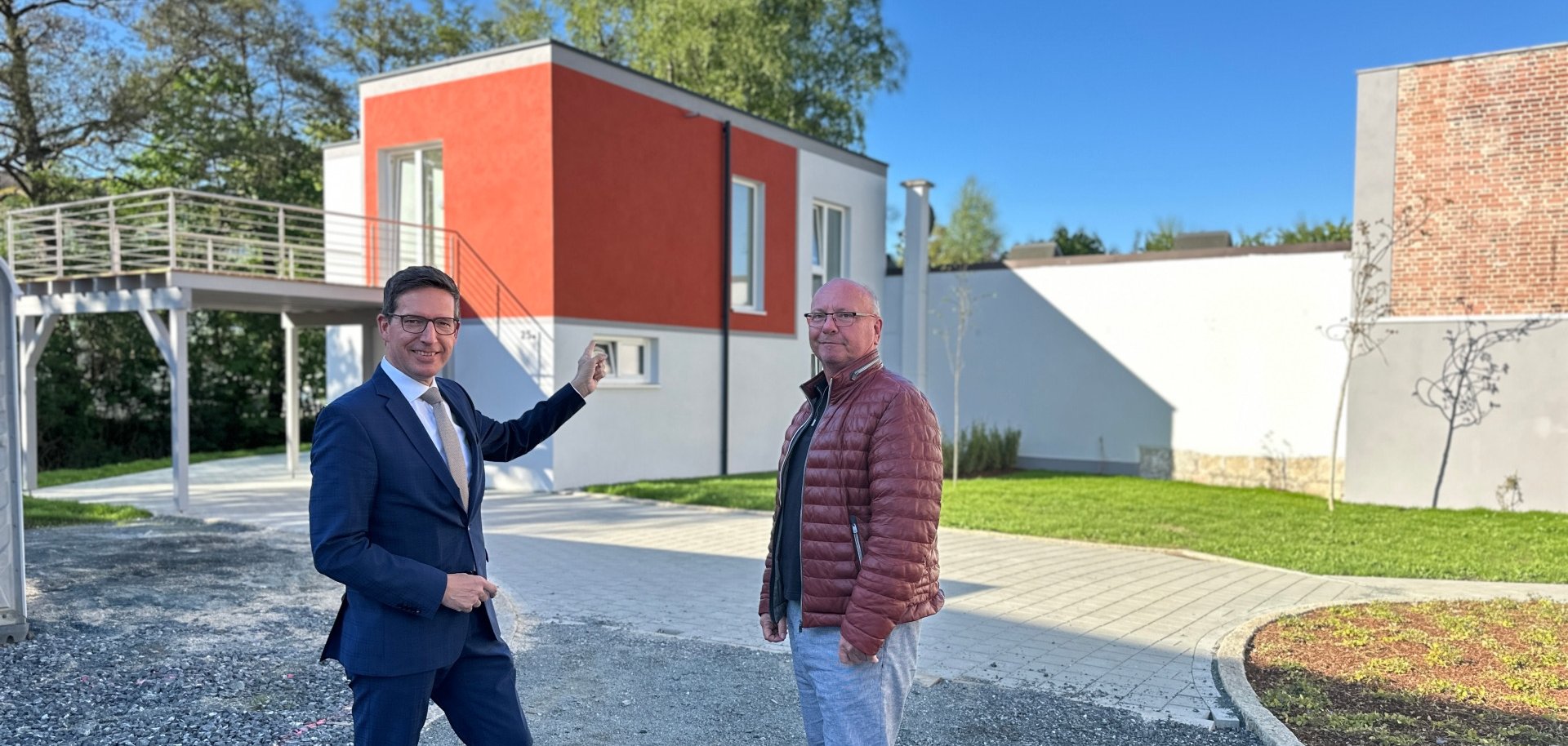 Auf dem Bild sind Bürgermeister Michael Abraham und Bauherr Matthias Stingl vor dem neuen Einfamilienhaus zu sehen.
