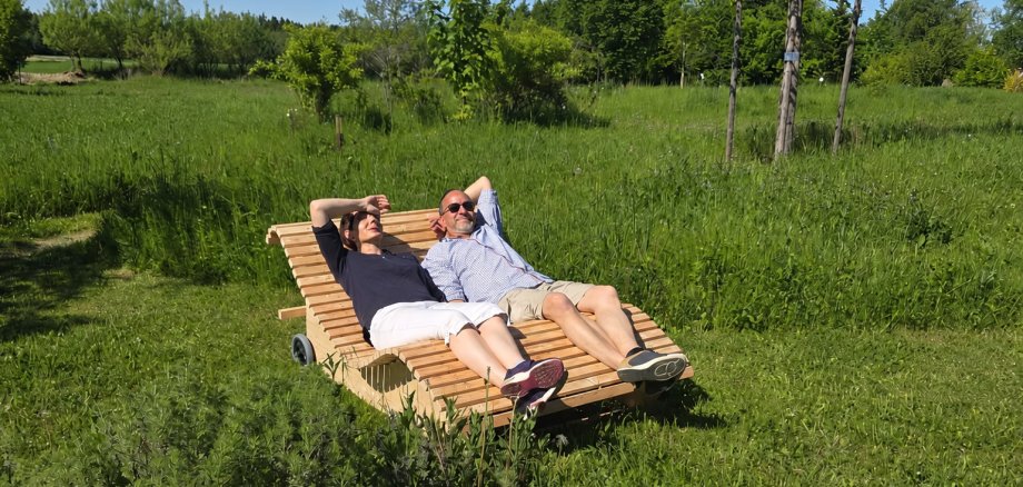 Das Bild zeigt zwei Personen, die auf einem der neuen Waldsofas liegen.