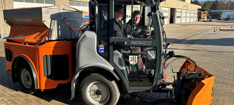 Das Bild zeigt den neuen Knickschlepper des städtischen Bauhofs, während Bürgermeister Abraham sich auf dem Fahrersitz die Funktionen von Bauhofleiter Mathias Winterling erklären lässt.