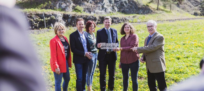 Das Bild zeigt Regina Saller (Landschaftspflegeverband Landkreis und Stadt Hof e.V.), Stefan Breuer (Bürgermeister Oberkotzau), Annette Bauer (Landschaftspflegeverband Landkreis und Stadt Hof e.V.), Landrat Dr. Oliver Bär, Isabel Kaske (Landschaftspflegeverband Landkreis und Stadt Hof e.V.) und Rudolf Scholz (2. Bürgermeister Rehau) auf dem neuen Themenwanderweg vor einer Wiese und der Bahnschiene.