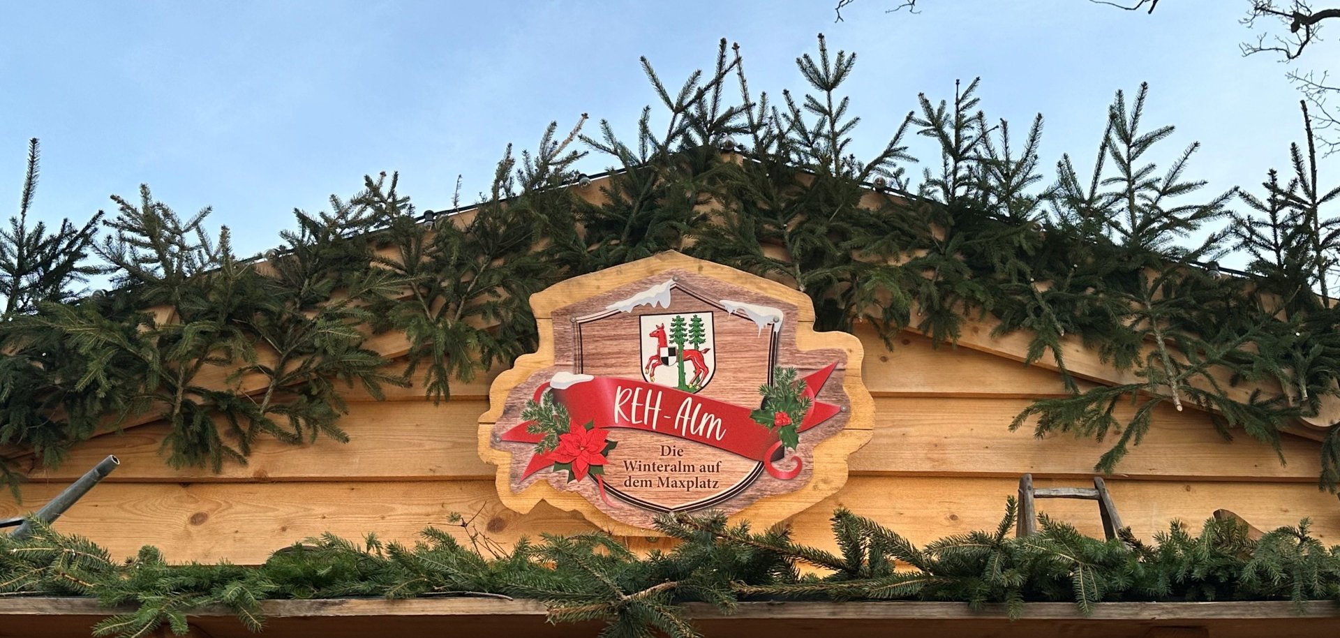 Das Bild zeigt das Außenschild der REH-Alm