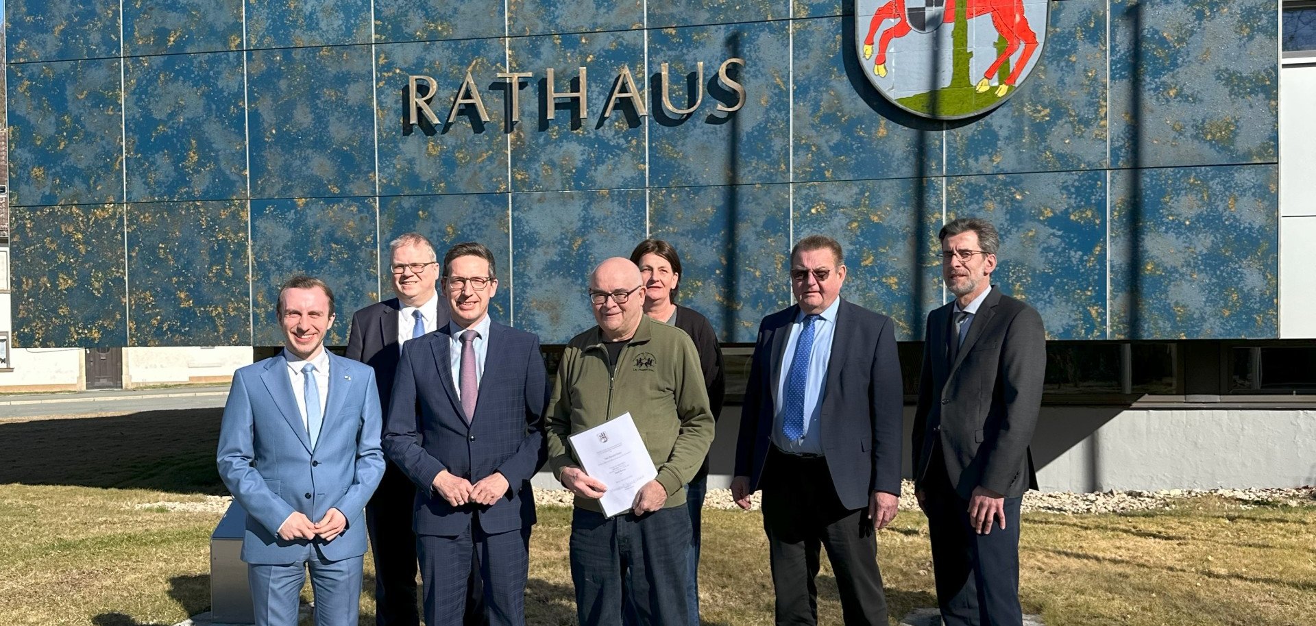 Das Bild zeigt ehemaligen Kassenleiter Ronald Geier, welcher von Bürgermeister Michael Abraham in den Ruhestand entlassen wurde. Außerdem sind auf dem Bild vor dem Rathaus zu sehen: Kämmerer Jan Muggenthaler, Ordnungsamtsleiter Frank Rameckers, Angestellte der Personalverwaltung Annett Vogel, Hauptamtsleiter Hans-Peter Zeeh sowie Wirtschaftsförderer Bernd Köppel.