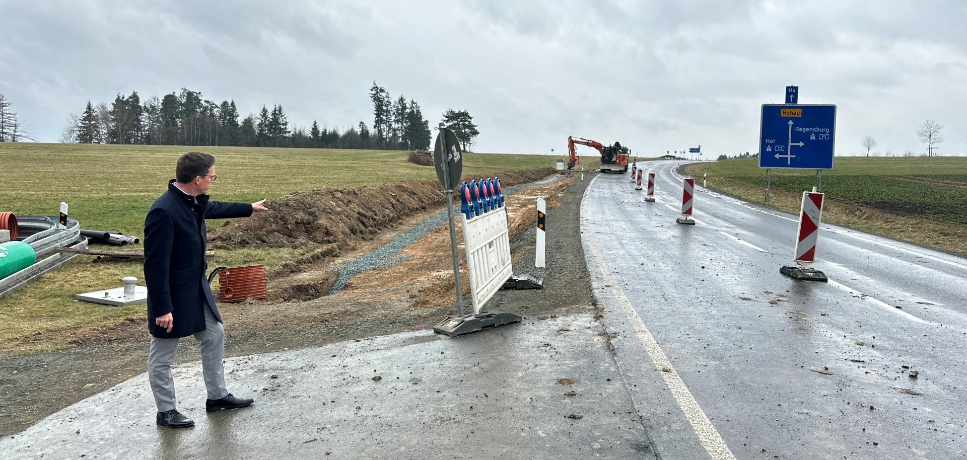 Das Bild zeigt Bürgermeister Abrahamim Baustellenbereich in Richtung der Bauarbeiten zum Radweg zeigend.