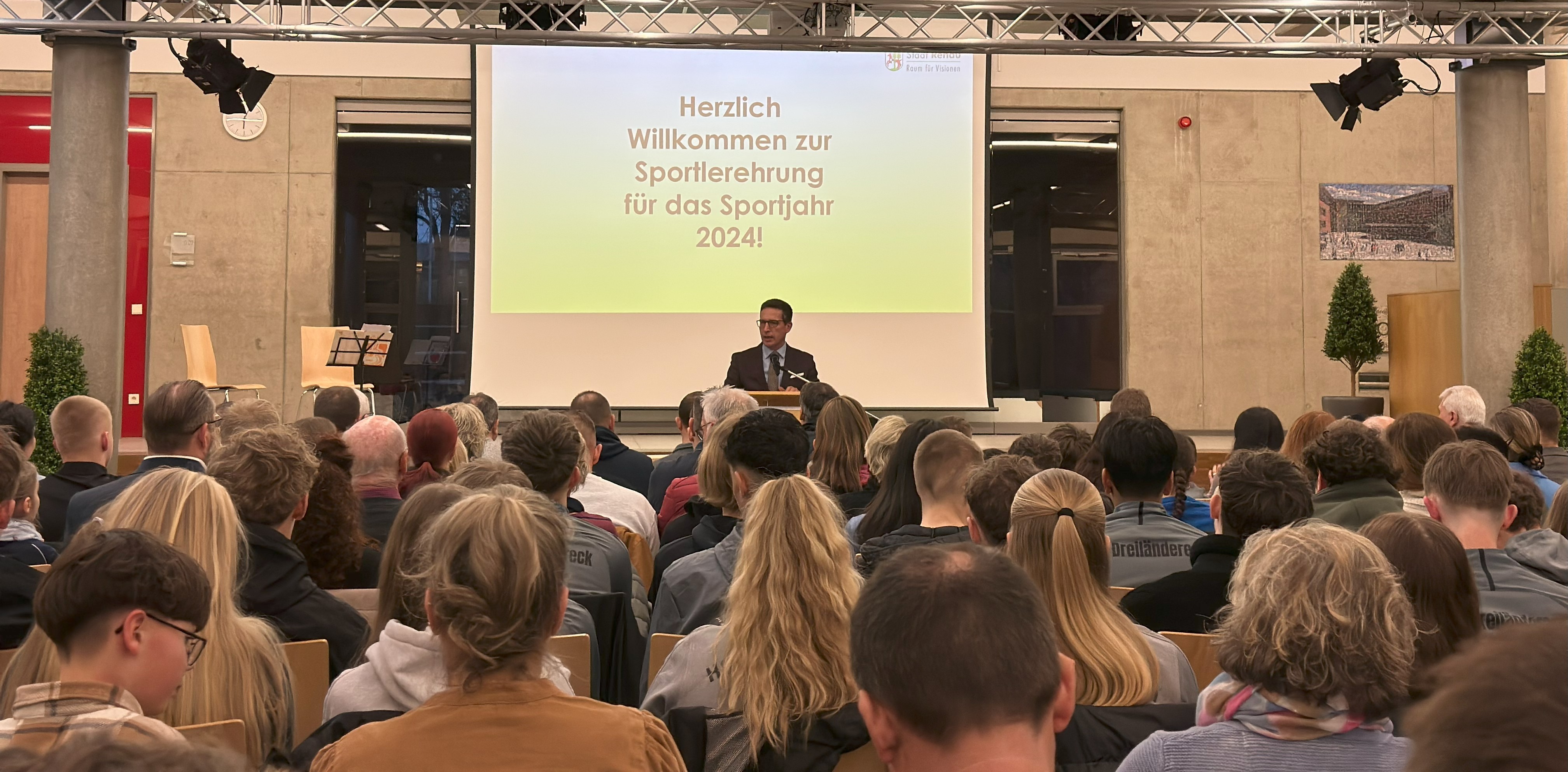 Das Bild zeigt Bürgermeister Abraham am Rednerpult vor den Sportlern.
