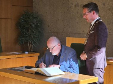 Auf dem Bild ist Harald Ehm zu sehen, wie er sich in das Goldene Buch der Stadt Rehau einträgt. Daneben steht Bürgermeister Abraham.