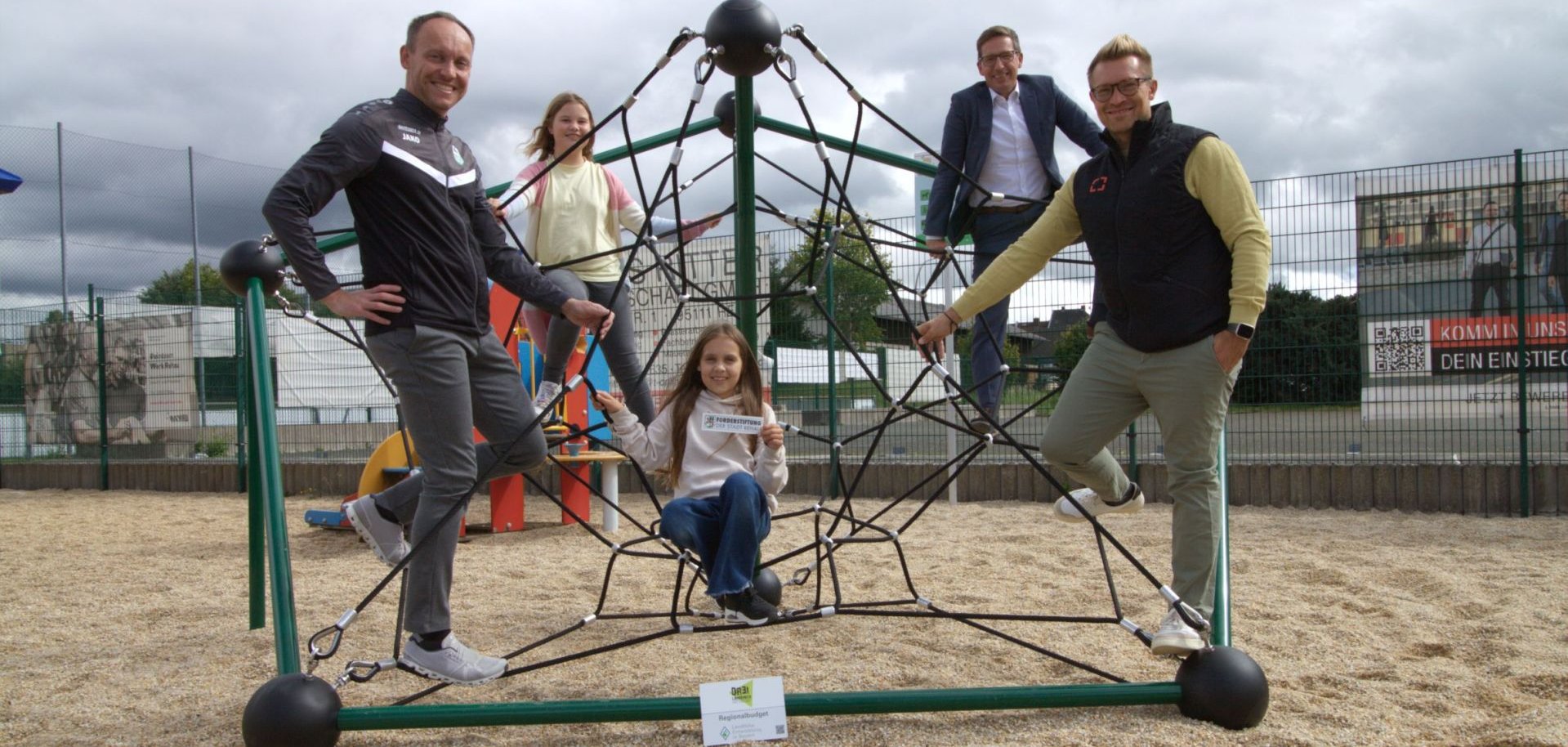 Das Bild zeigt Bürgermeister Michael Abraham auf dem neuen Kletter-Oktagon auf dem Spielplatz des VfB Rehau mit Vertretern des Vereins.