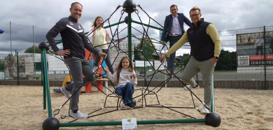 Das Bild zeigt Bürgermeister Michael Abraham auf dem neuen Kletter-Oktagon auf dem Spielplatz des VfB Rehau mit Vertretern des Vereins.