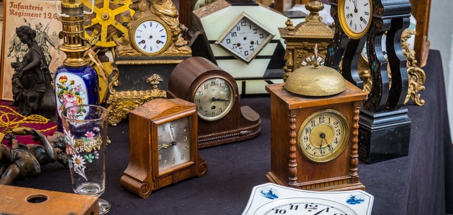 Das Bild zeigt einige alte Standuhren, teilweise schon ohne Zeiger.