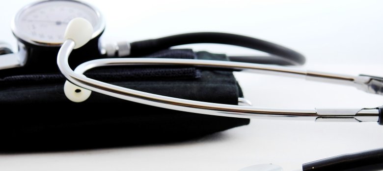 Das Bild zeigt im Vordergrund Teile eines Stethoskops. Im Hintergrund ist weiteres Zubehör eines Arztes zu sehen.