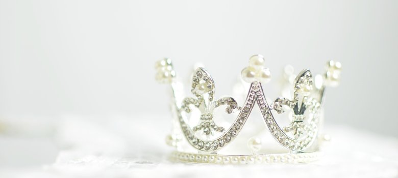 Das Bild zeigt eine Krone mit Glitzersteinen und Perlen.