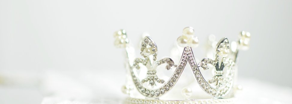 Das Bild zeigt eine Krone mit Glitzersteinen und Perlen.