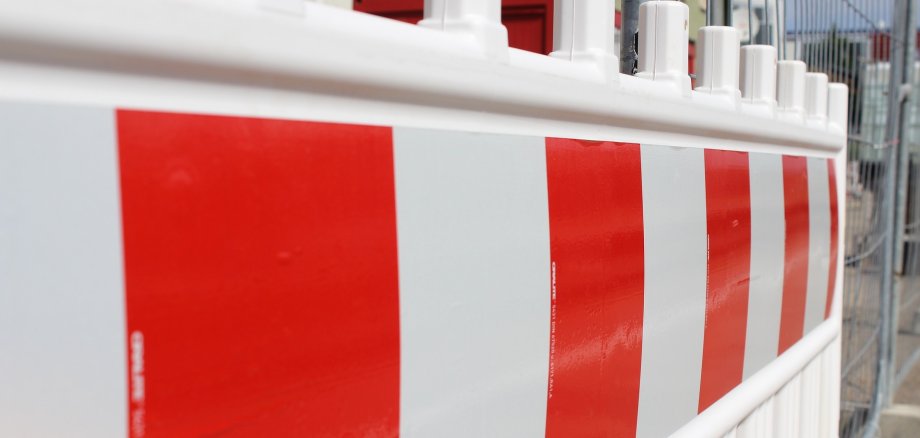 Auf dem Bild ist eine rot-weiße Straßenabsperrung zu sehen. 