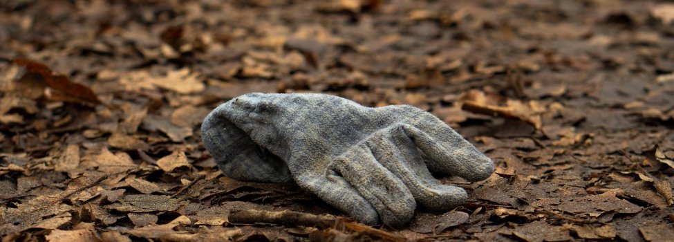 Auf dem Bild ist ein grauer Handschuh zu sehen, der auf dem Boden liegt.
