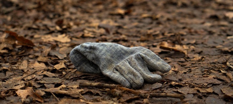 Auf dem Bild ist ein grauer Handschuh zu sehen, der auf dem Boden liegt.