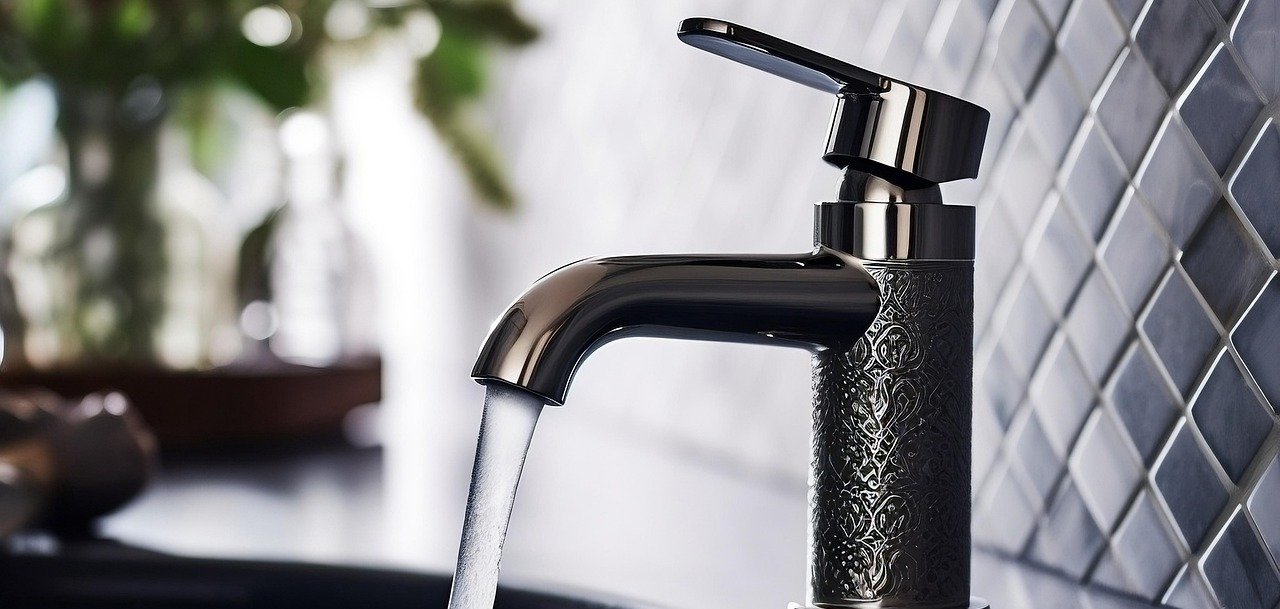 Auf dem Bild ist ein Wasserhahn an einem Waschbecken zu sehen, der gerade aufgedreht ist.