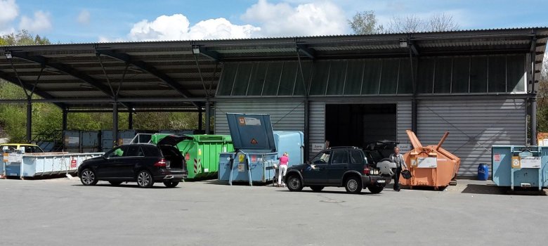Auf dem Bild ist der Wertstoffhof zu sehen. Dort stehen ein paar Autos und Container.