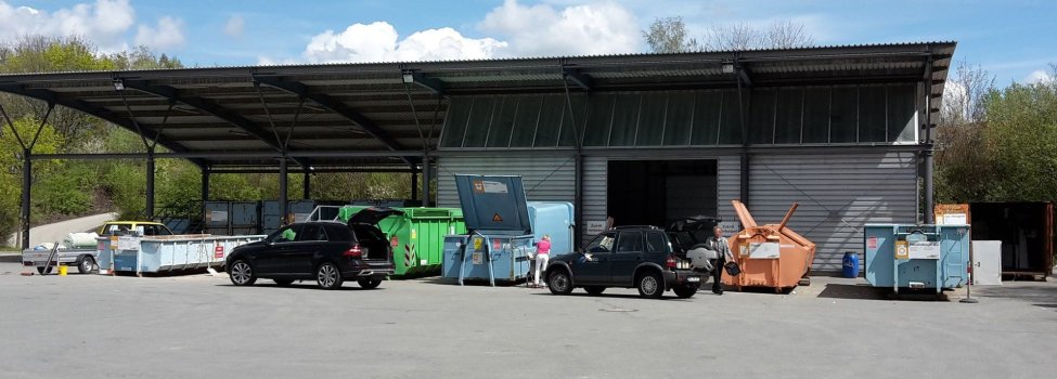 Auf dem Bild ist der Wertstoffhof zu sehen. Dort stehen ein paar Autos und Container.