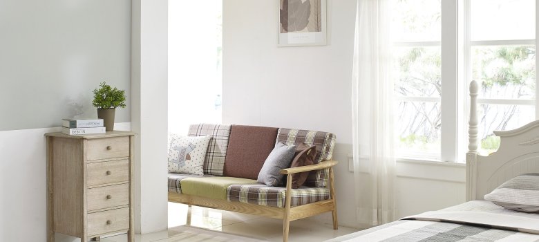 Auf dem Bild ist ein heller Wohnraum mit Bett und Sitzbank zu sehen.