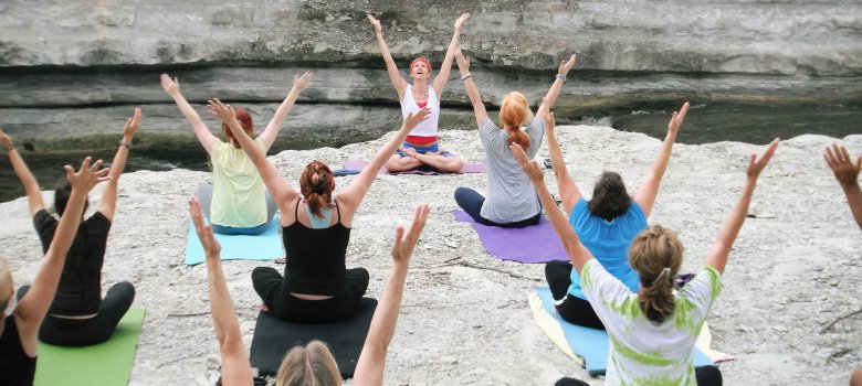 Auf dem Bild sind mehrere Personen zu sehen, die Yoga machen. 