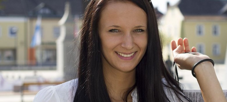 Das Bild zeigt eine dunkelhaarige Dame mit einer Einkaufstasche über den Schultern.