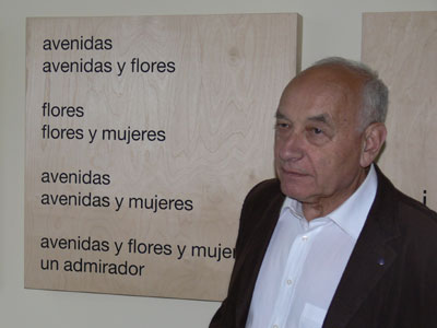 Das Bild zeigt Prof. Eugen Gomringer. Er steht vor seinem Gedicht "avenidas".