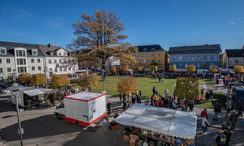 Das Bild zeigt eine vergangene Herbstmarkt-Veranstaltung. Darauf zu erkennen sind verschiedene Stände rund um den Maxplatz sowie viele Besucher über den ganzen Platz verteilt. Aufgenommen wurde das Bild vom Balkon des Alten Rathauses aus.