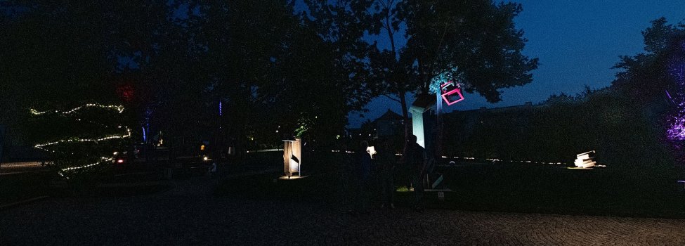 Das Bild zeigt den farblich beleuchteten Skulpturengarten bei Nacht.