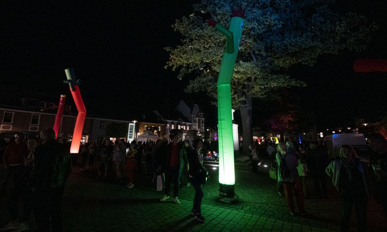 Das Bild zeigt viele Besucher auf dem Maxplatz bei Dunkelheit. Farblich beleuchtete, aufblasbare Figuren setzen helle Akzente.