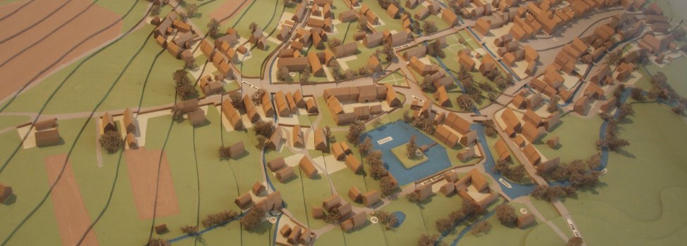 Das Bild zeigt ein Stadtmodell von Rehau, welches Rehau vor vielen Jahren abbildet. Zu erkennen sind Gewässer, Häuser, Bäume und damalige Wege.