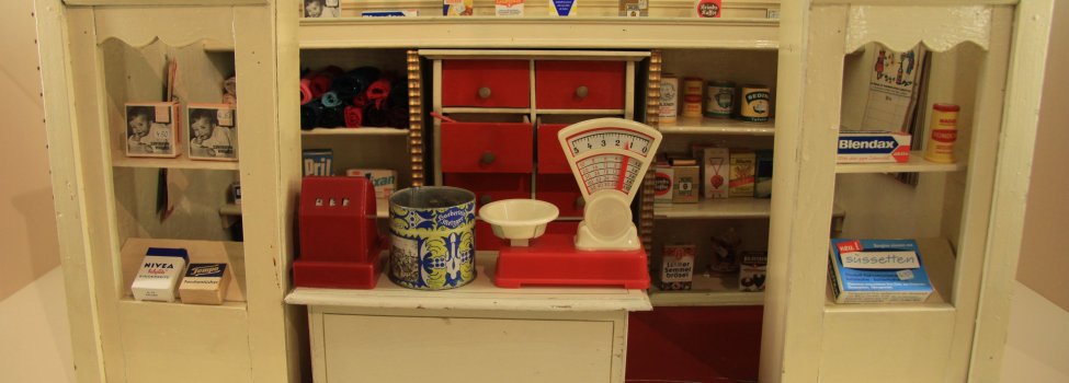 Das Bild zeigt Bestandteile der Puppen- und Spielzeugsammlung im Rehauer Museum. Konkret ist ein winziger Kaufladen mit verschiedenen Artikeln wie Tempo-Taschentüchern zu erkennen.