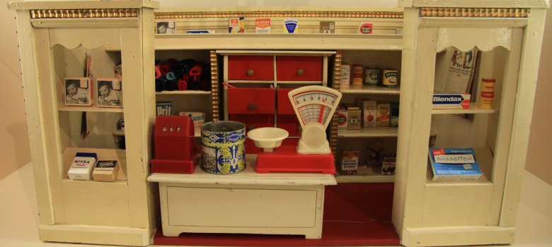 Das Bild zeigt Bestandteile der Puppen- und Spielzeugsammlung im Rehauer Museum. Konkret ist ein winziger Kaufladen mit verschiedenen Artikeln wie Tempo-Taschentüchern zu erkennen.