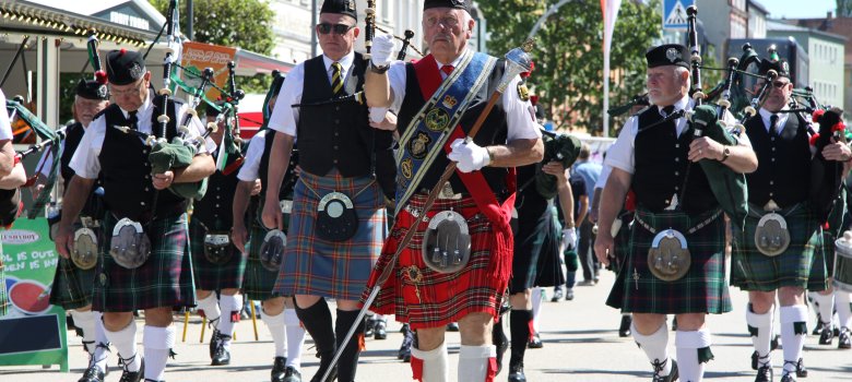 Das Bild zeigt eine schottische Gruppe mit Dudelsäcken, welche im Festzug durch eine Straße in Rehau laufen.