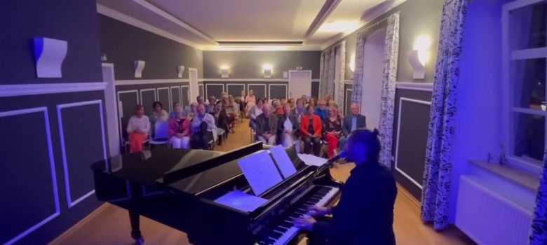 Das Bild zeigt eine Veranstaltung im Festsaal des Alten Rathauses. Im Vordergrund ist ein Musiker am Flügel zu sehen. Dahinter sitzen die Zuhörer.